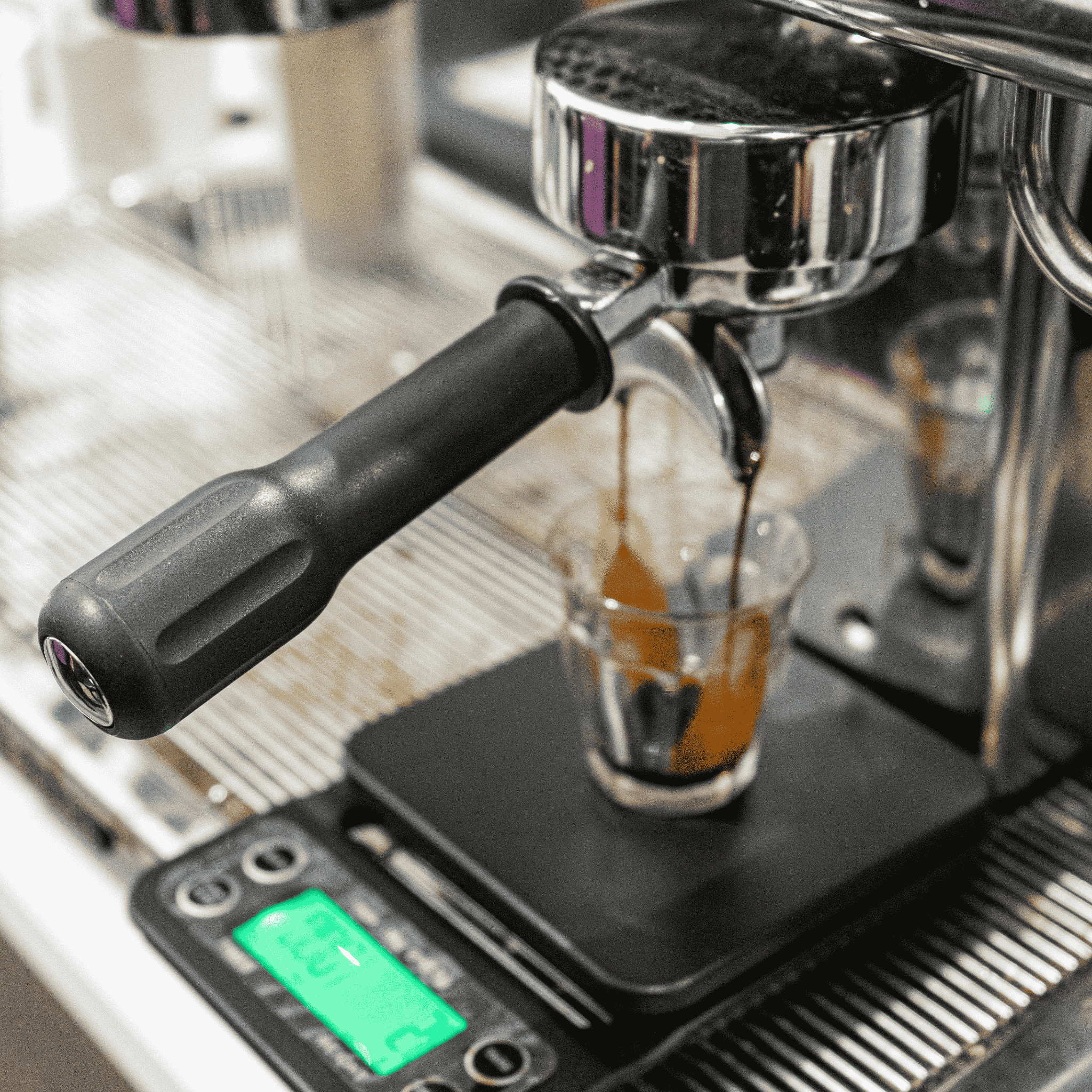 Espresso machine dispensing coffee into a glass on a digital scale.